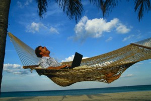 Man with Laptop Computer in Hammock on the Beach